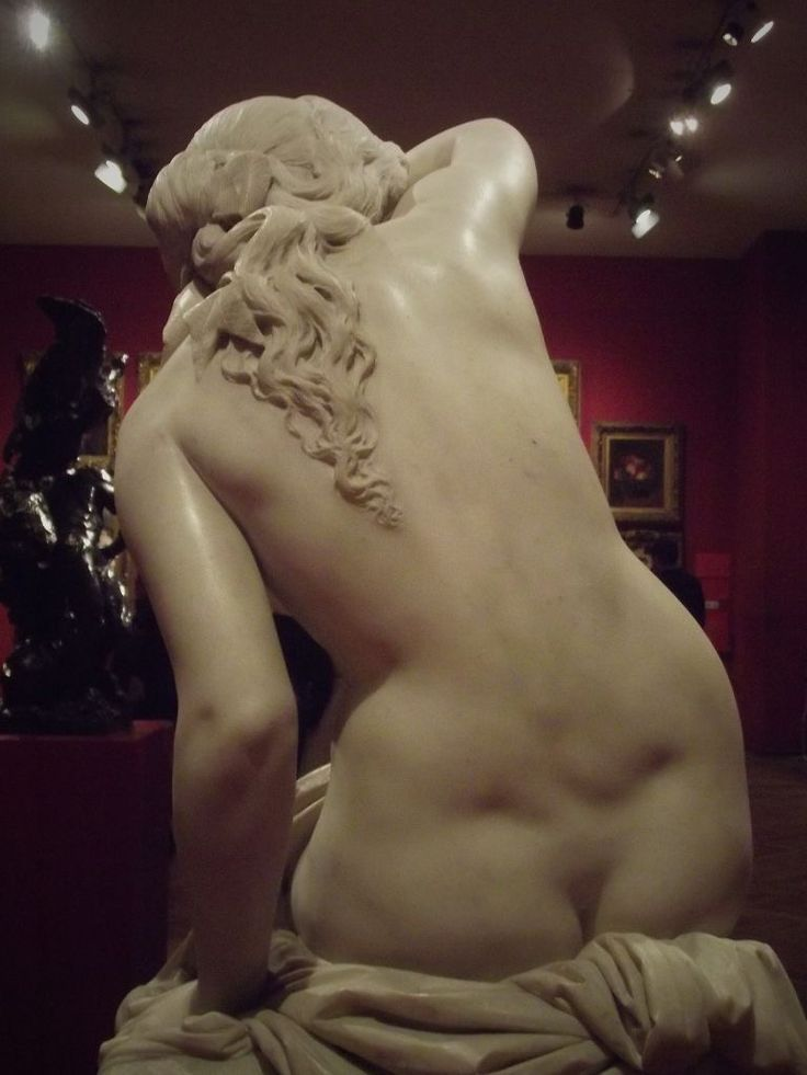 Marble sculpture of a reclining nude figure in a museum gallery.