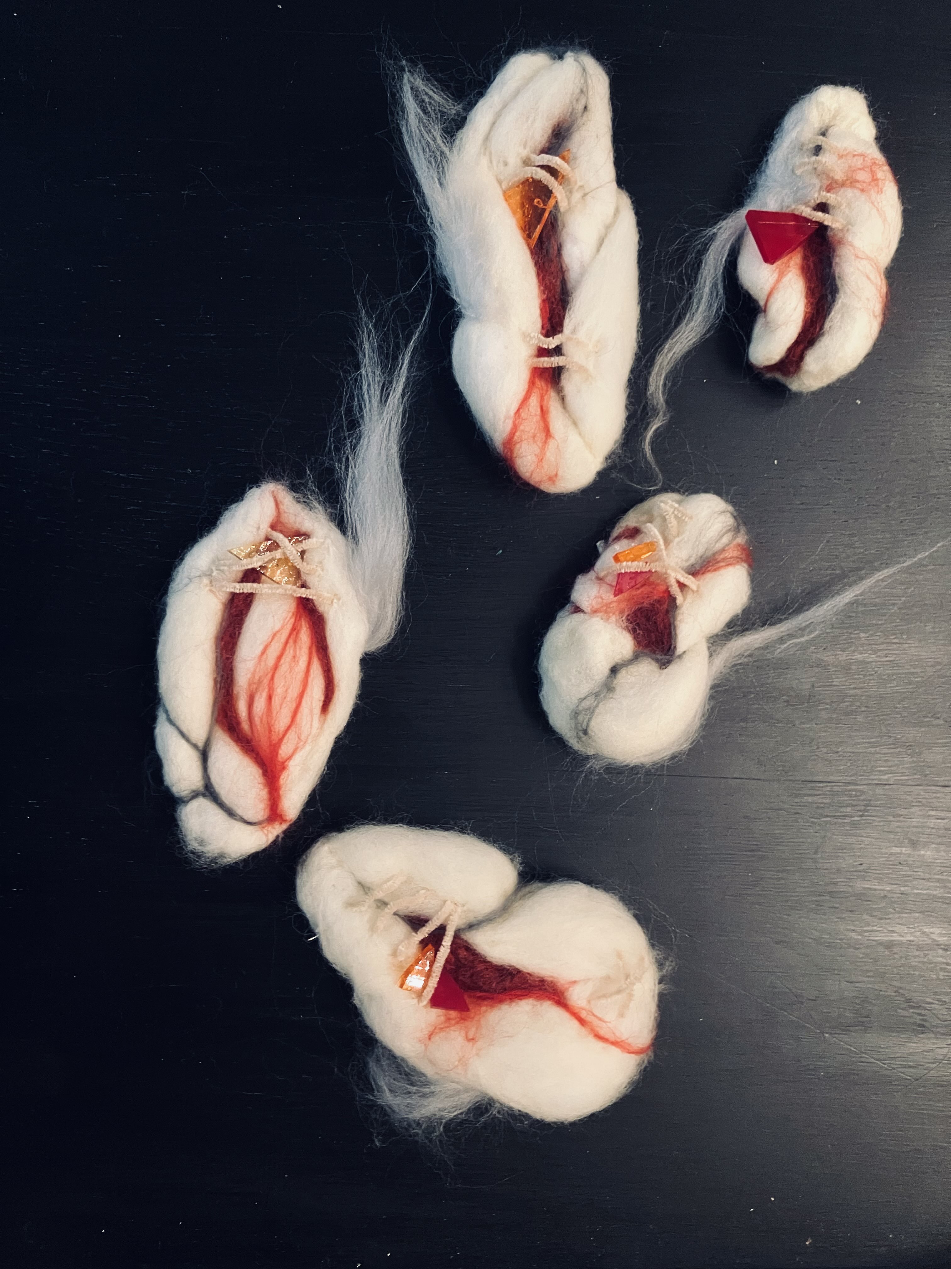 Soft sculptural relics arranged on a dark surface.
