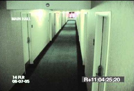 A surveillance image of a long, empty institutional corridor.
