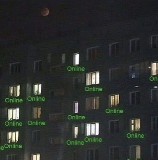 A dark apartment building with illuminated windows marked online.
